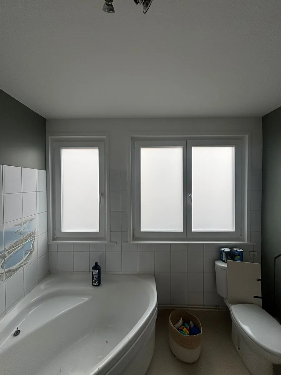 Film dépoli sur fenêtre de salle de bain avec baignoire